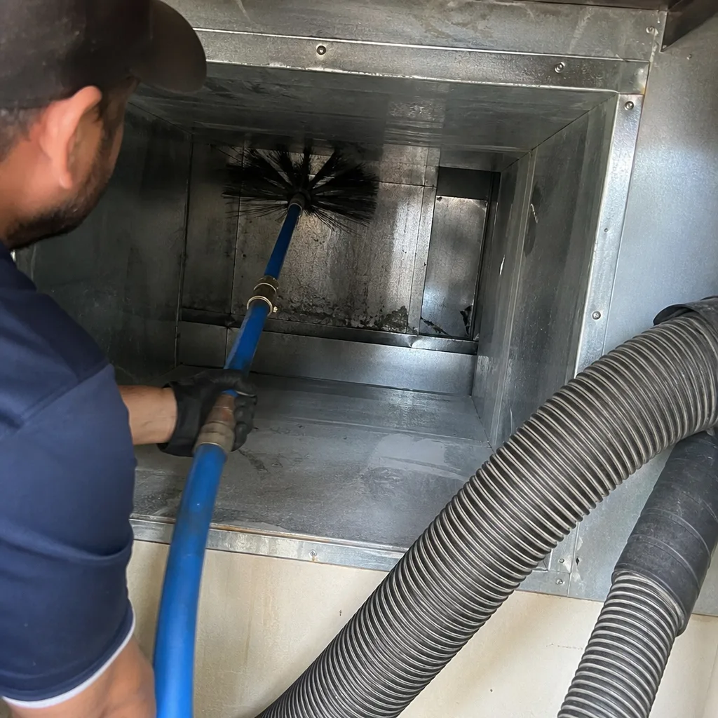 Technician using a rotating brush tool for professional air duct cleaning.